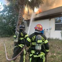 Firefighters standing in front of a structure on fire